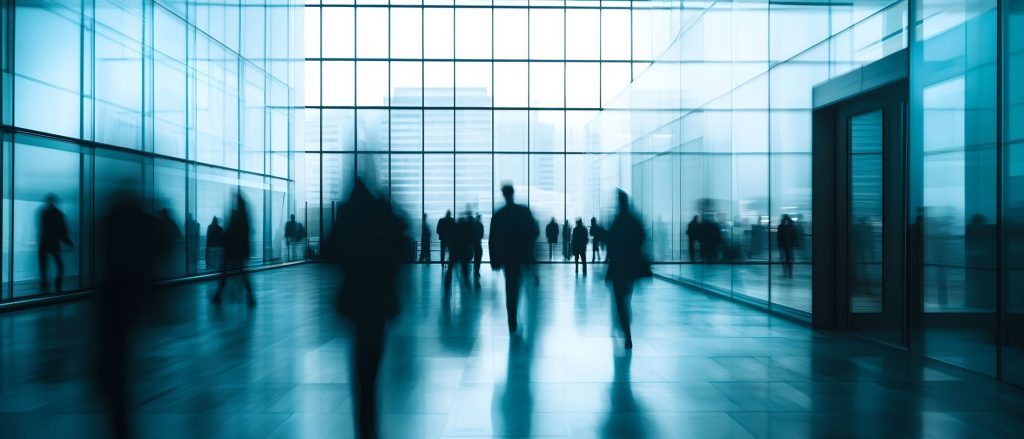 People crossing a glass-walled corporate lobby